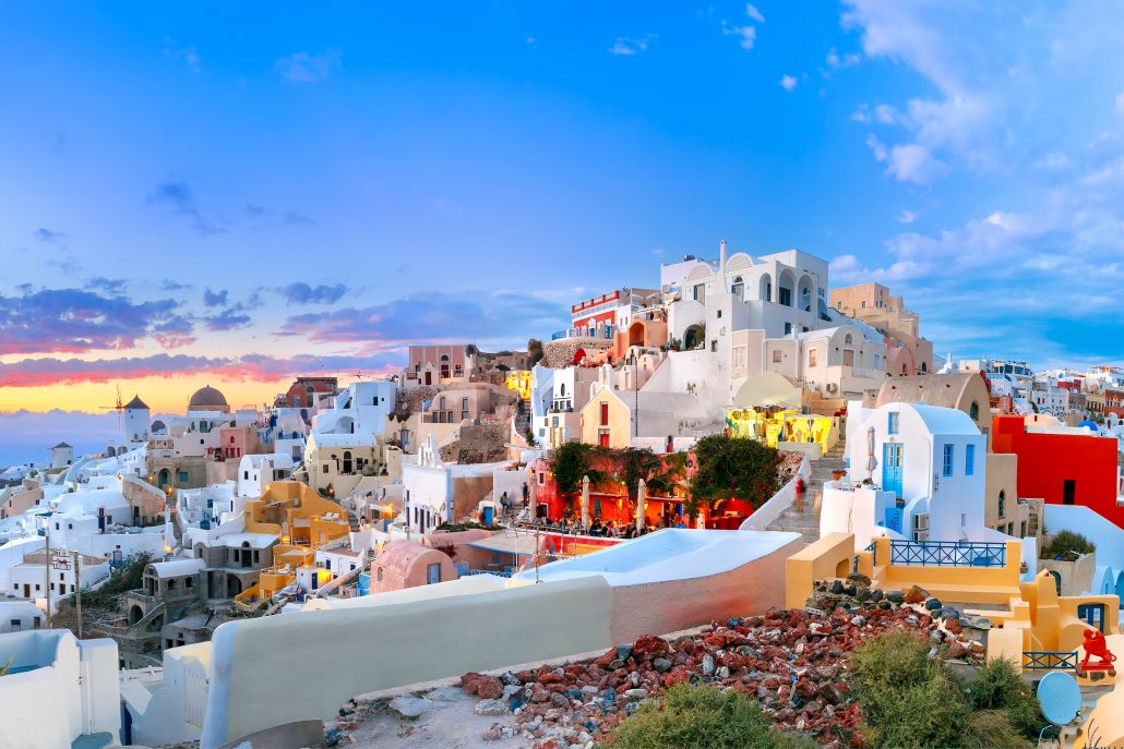 Old Town of Oia or Ia on the island Santorini, white houses, windmills and church with blue domes at sunset, Greece-min