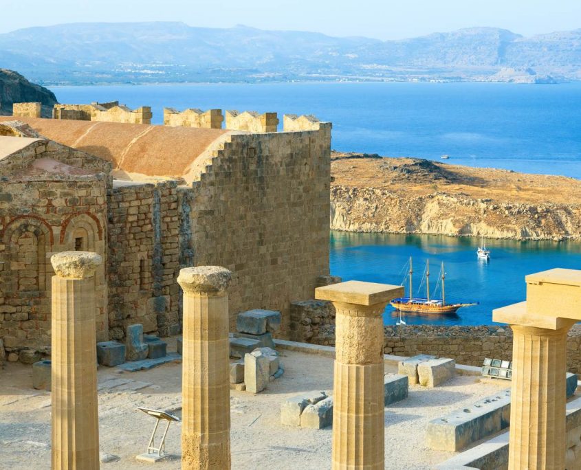 Panoramic view of Doris Temple of Athena Lindia, medieval castle on Acropolis of Lindos with blue bay beneath, Rhodes Island